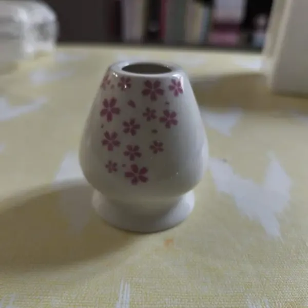 Sakura glaze ceramic matcha whisk holder on a yellow tablecloth, buyer photo